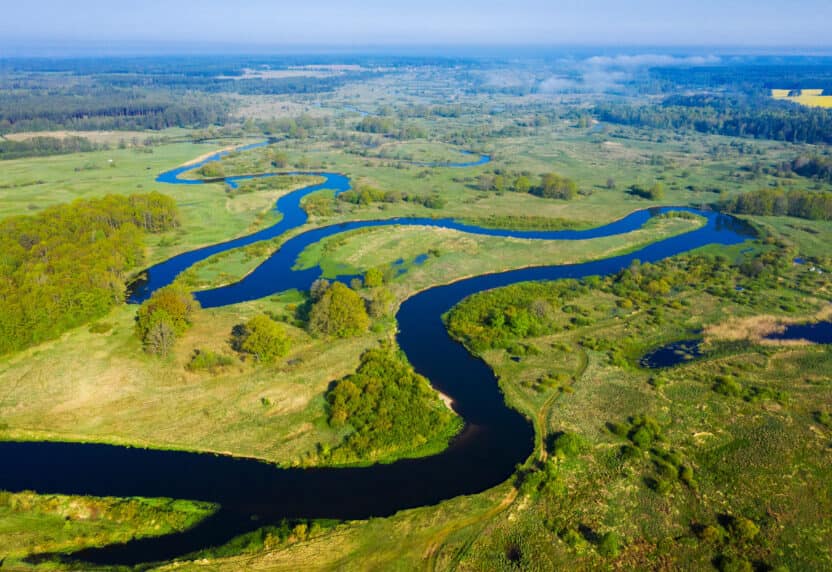 Aerial nature river background. Scenic river on green meadow from above. Drone view on curved river